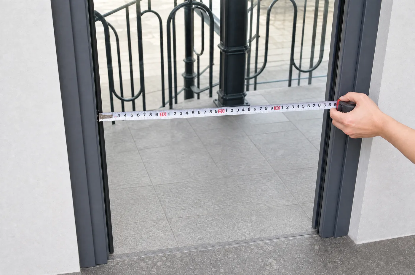 Fita métrica esticada na horizontal no vão livre da porta, do bordo interior do aro à esquerda até ao da direita